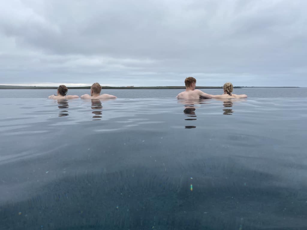 People enjoying the ocean view while bathing in the warm geothermal Sky Lagoon spa